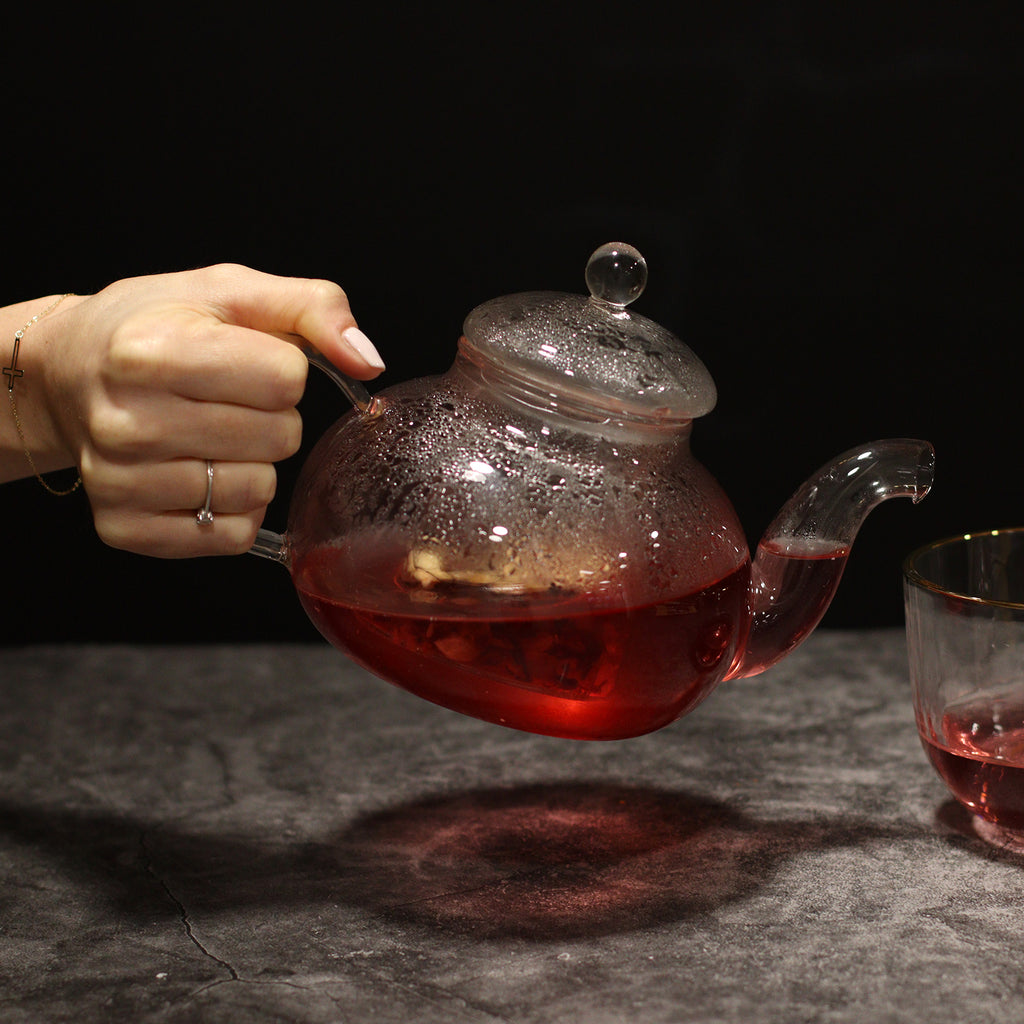 Transparente Glasteekanne Round Pearl mit Glasfilter – 800 ml, beim Ausgießen von rotem Tee
